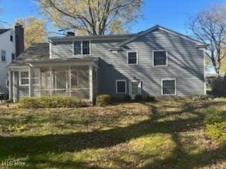 rear view of house with a chimney and a sunroom