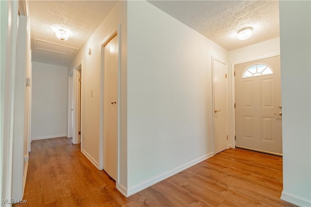 entrance foyer featuring light wood-type flooring, a textured ceiling, and baseboards