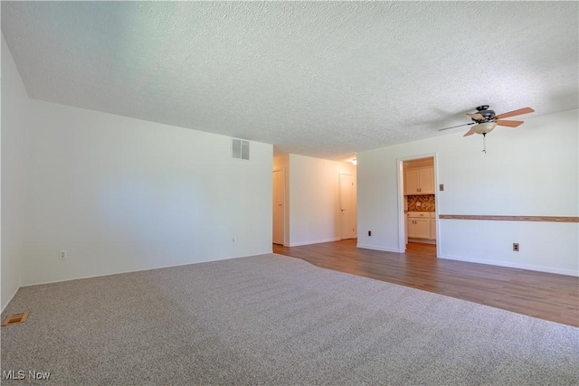 empty room featuring visible vents, carpet flooring, a textured ceiling, and ceiling fan