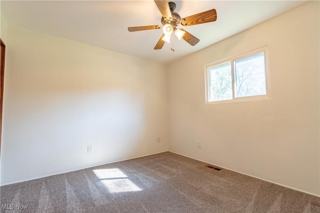 carpeted spare room with a ceiling fan and visible vents