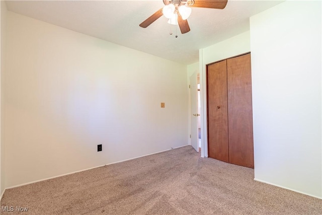 unfurnished bedroom featuring ceiling fan, a closet, and light colored carpet