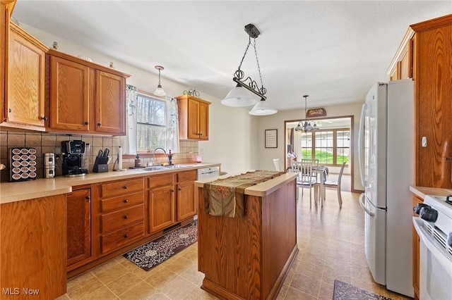 409 Pin Oak Pl, Campbell, OH 44405 - kitchen with a sink, white appliances, light countertops, tasteful backsplash, and a kitchen island