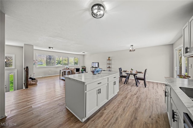 6084 Clay St, Thompson, OH 44086 - kitchen with wood finished floors, a kitchen island, light stone countertops, baseboards, and dishwasher