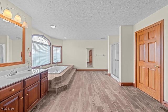 275 Camden Ln, Aurora, OH 44202 - full bathroom featuring vanity, wood finished floors, a textured ceiling, a bath, and a shower stall