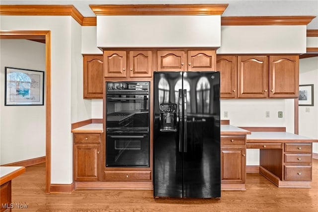 275 Camden Ln, Aurora, OH 44202 - kitchen featuring crown molding, brown cabinetry, light countertops, light wood finished floors, and black appliances
