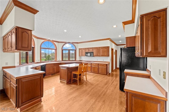 275 Camden Ln, Aurora, OH 44202 - kitchen featuring brown cabinetry, crown molding, black appliances, a peninsula, and light wood-style flooring