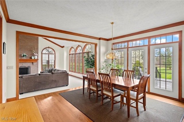 275 Camden Ln, Aurora, OH 44202 - dining room featuring crown molding, a textured ceiling, a brick fireplace, and wood finished floors