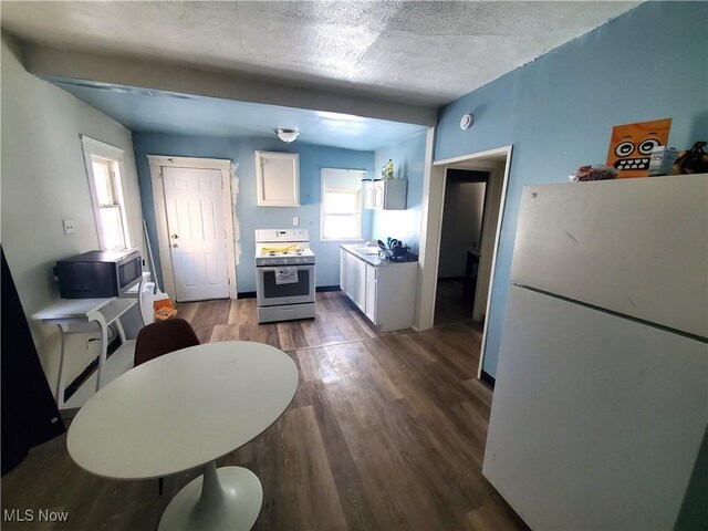 9615 Dunlap Ave, Cleveland, OH 44105 - kitchen with range with gas cooktop, wood finished floors, stainless steel microwave, freestanding refrigerator, and white cabinetry