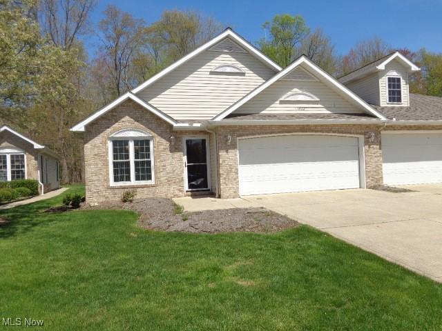 view of front of property featuring brick siding, a garage, a front lawn, and driveway