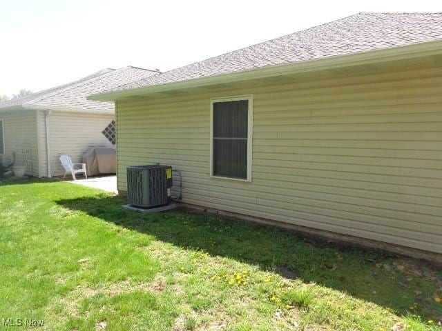view of property exterior with central air condition unit and a yard