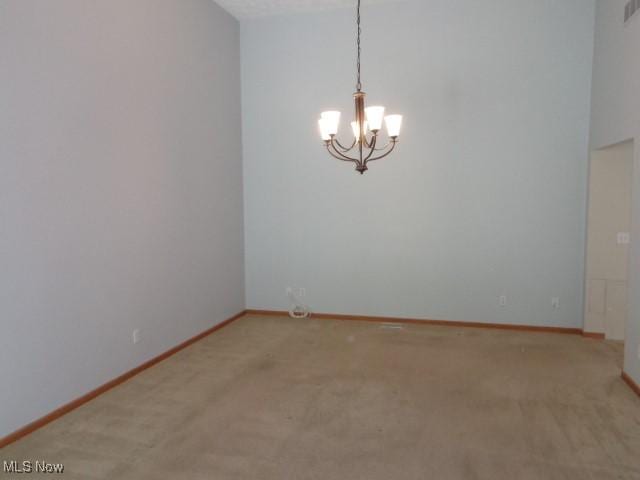 spare room featuring carpet floors, baseboards, a notable chandelier, and visible vents