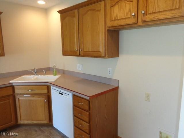 kitchen with brown cabinetry, white dishwasher, a sink, and light countertops