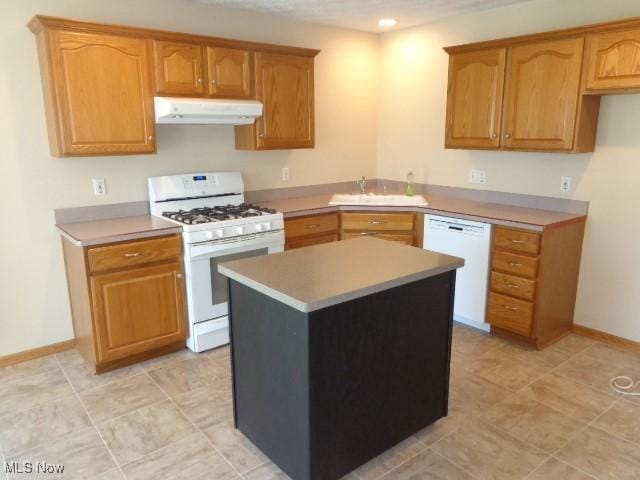 kitchen featuring white appliances, baseboards, under cabinet range hood, and a sink