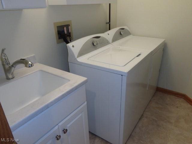 laundry area featuring a sink, washing machine and dryer, and cabinet space