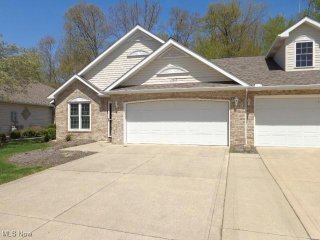 view of front facade with brick siding, an attached garage, and driveway