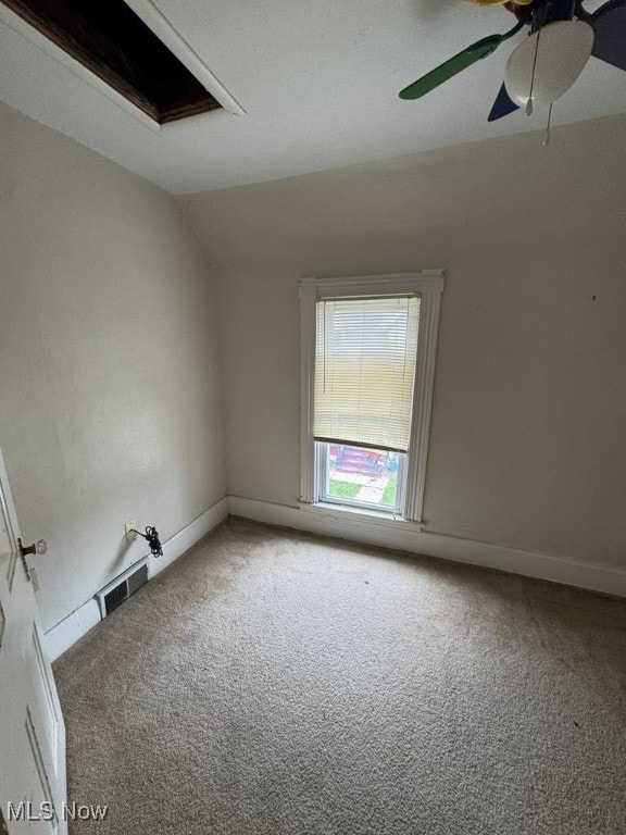 unfurnished room featuring light carpet, a ceiling fan, baseboards, lofted ceiling, and visible vents