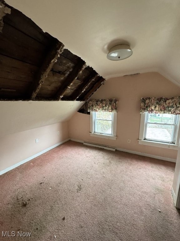 additional living space featuring baseboards, vaulted ceiling, carpet flooring, and a baseboard heating unit