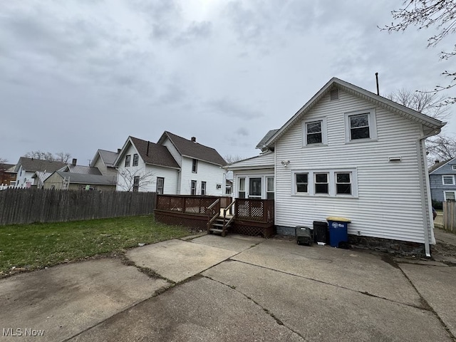 back of property featuring a lawn, a patio, fence, and a wooden deck
