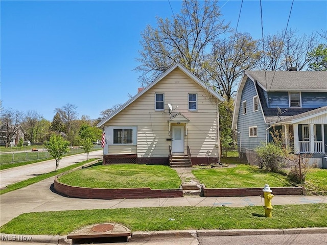 bungalow-style house featuring a front lawn, fence, and entry steps