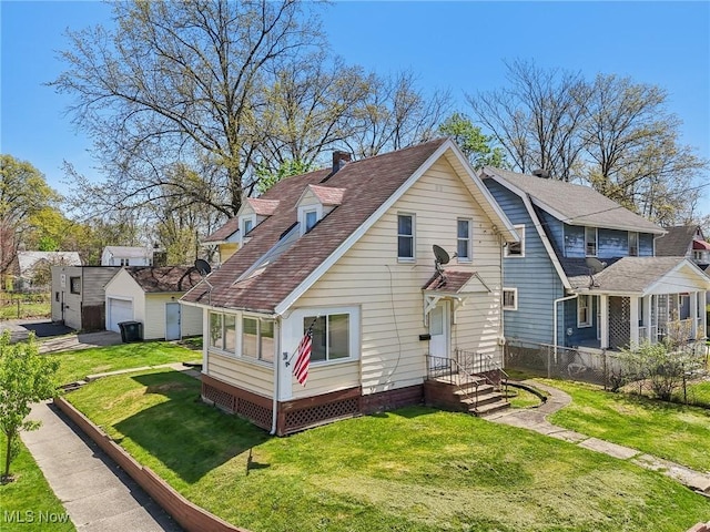 rear view of house with fence, a detached garage, a yard, and roof with shingles