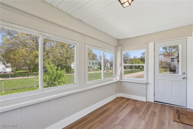 unfurnished sunroom featuring baseboards and wood finished floors