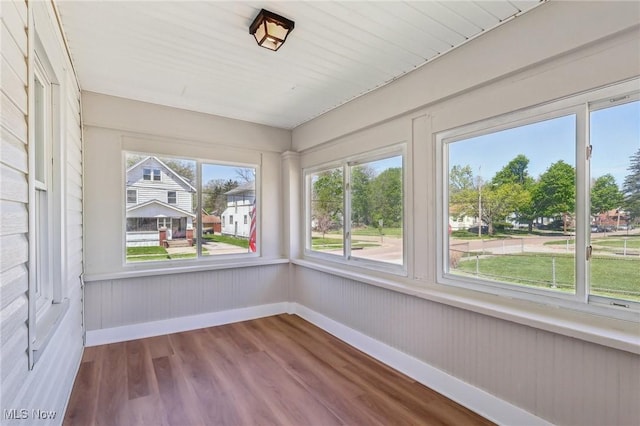 unfurnished sunroom featuring baseboards and wood finished floors