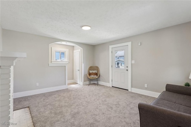 living room with arched walkways, baseboards, carpet, and a textured ceiling