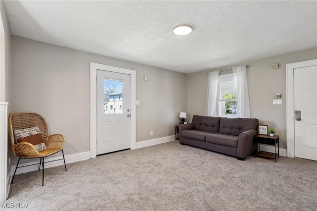 carpeted living area featuring baseboards and a textured ceiling