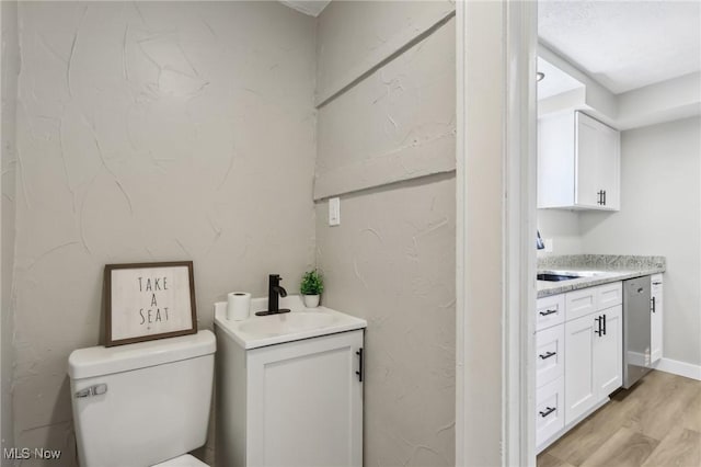 half bathroom with toilet, wood finished floors, and vanity