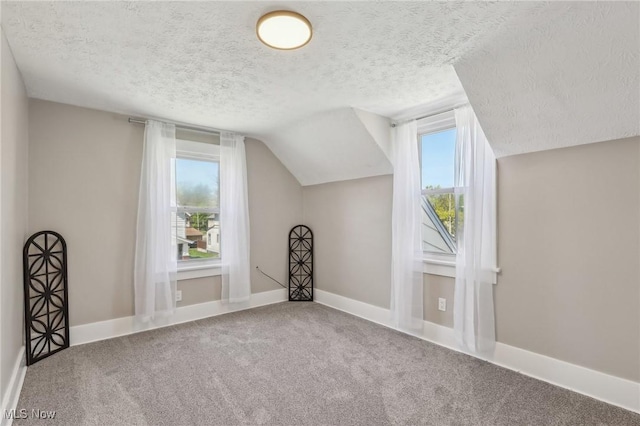bonus room with baseboards, carpet flooring, a textured ceiling, and lofted ceiling