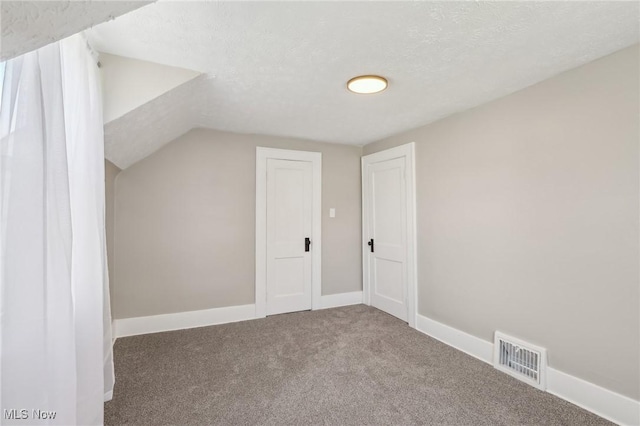 bonus room with visible vents, baseboards, a textured ceiling, carpet flooring, and vaulted ceiling