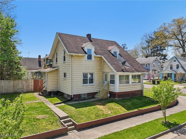view of front of home with fence, roof with shingles, a front yard, entry steps, and a chimney