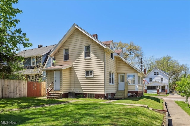 back of house with a chimney, a lawn, central air condition unit, fence, and entry steps