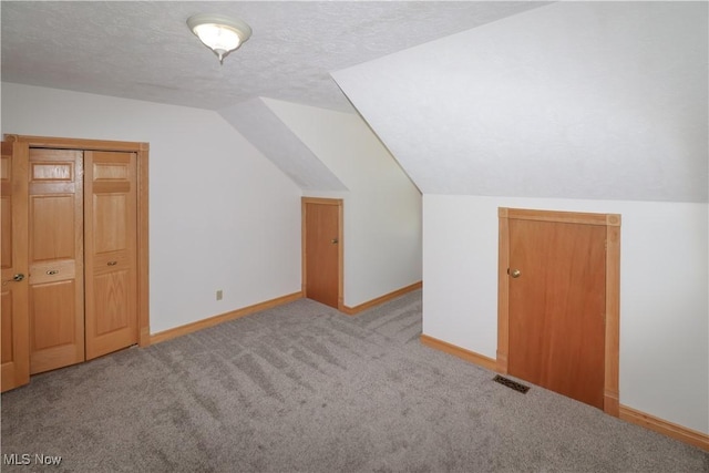 bonus room featuring visible vents, lofted ceiling, baseboards, a textured ceiling, and carpet