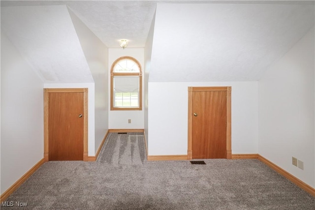 bonus room featuring baseboards, carpet floors, lofted ceiling, and visible vents