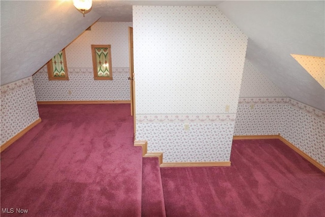 additional living space with carpet floors, vaulted ceiling, and wallpapered walls