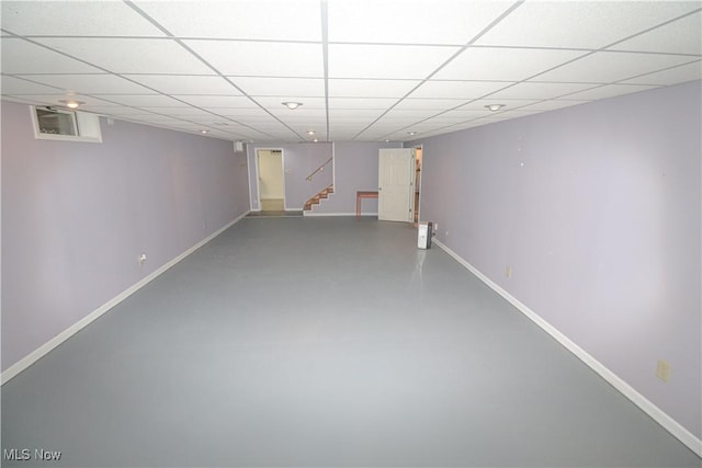 finished below grade area with baseboards, stairs, and a paneled ceiling
