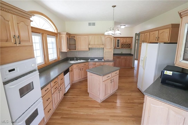 kitchen featuring visible vents, white appliances, dark countertops, a center island, and light wood-type flooring