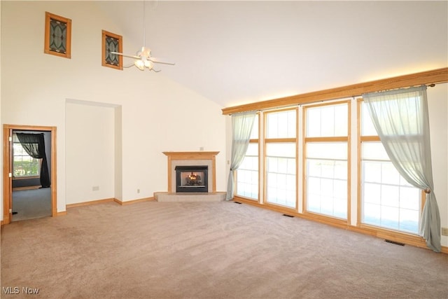 unfurnished living room with carpet flooring, a fireplace with raised hearth, a ceiling fan, baseboards, and visible vents