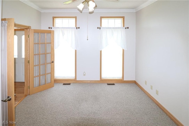 carpeted spare room featuring visible vents, ornamental molding, and a ceiling fan