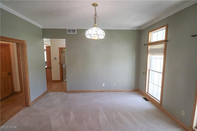 empty room with baseboards, light colored carpet, ornamental molding, and visible vents