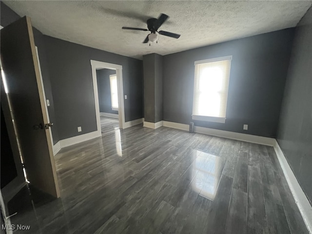 empty room featuring baseboards, a ceiling fan, dark wood-style flooring, and a textured ceiling