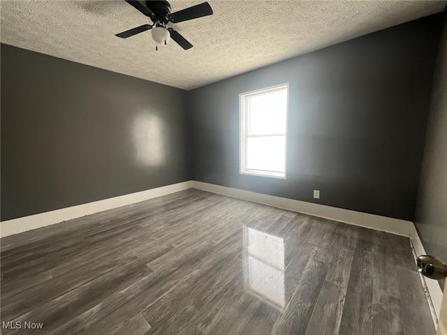 spare room with baseboards, a ceiling fan, dark wood-style flooring, and a textured ceiling