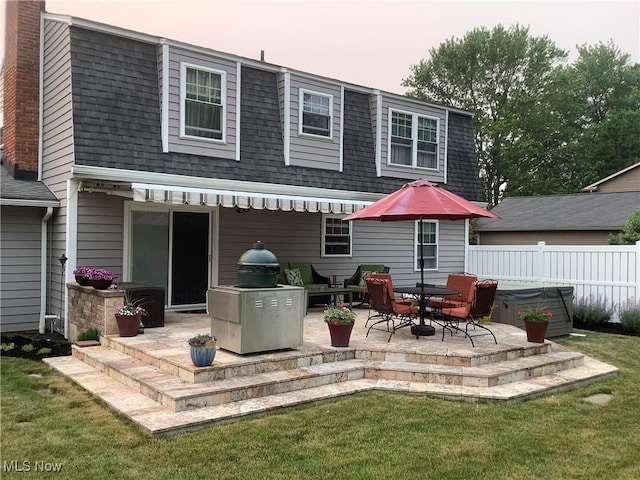 rear view of property featuring fence, roof with shingles, mansard roof, a patio area, and a yard