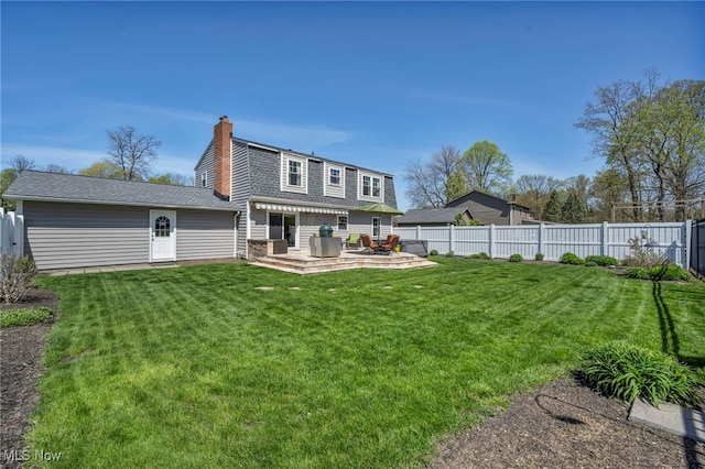 rear view of property featuring roof with shingles, a wooden deck, a fenced backyard, a chimney, and a yard