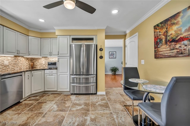 kitchen with ornamental molding, a ceiling fan, stone finish flooring, backsplash, and stainless steel appliances