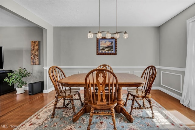 dining space featuring wood finished floors and a wainscoted wall