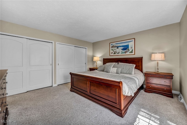 carpeted bedroom featuring multiple closets, baseboards, and a textured ceiling