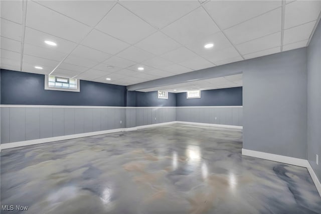 basement with recessed lighting, baseboards, a drop ceiling, and wainscoting