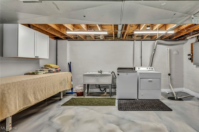 clothes washing area with a sink, electric panel, cabinet space, and washing machine and clothes dryer